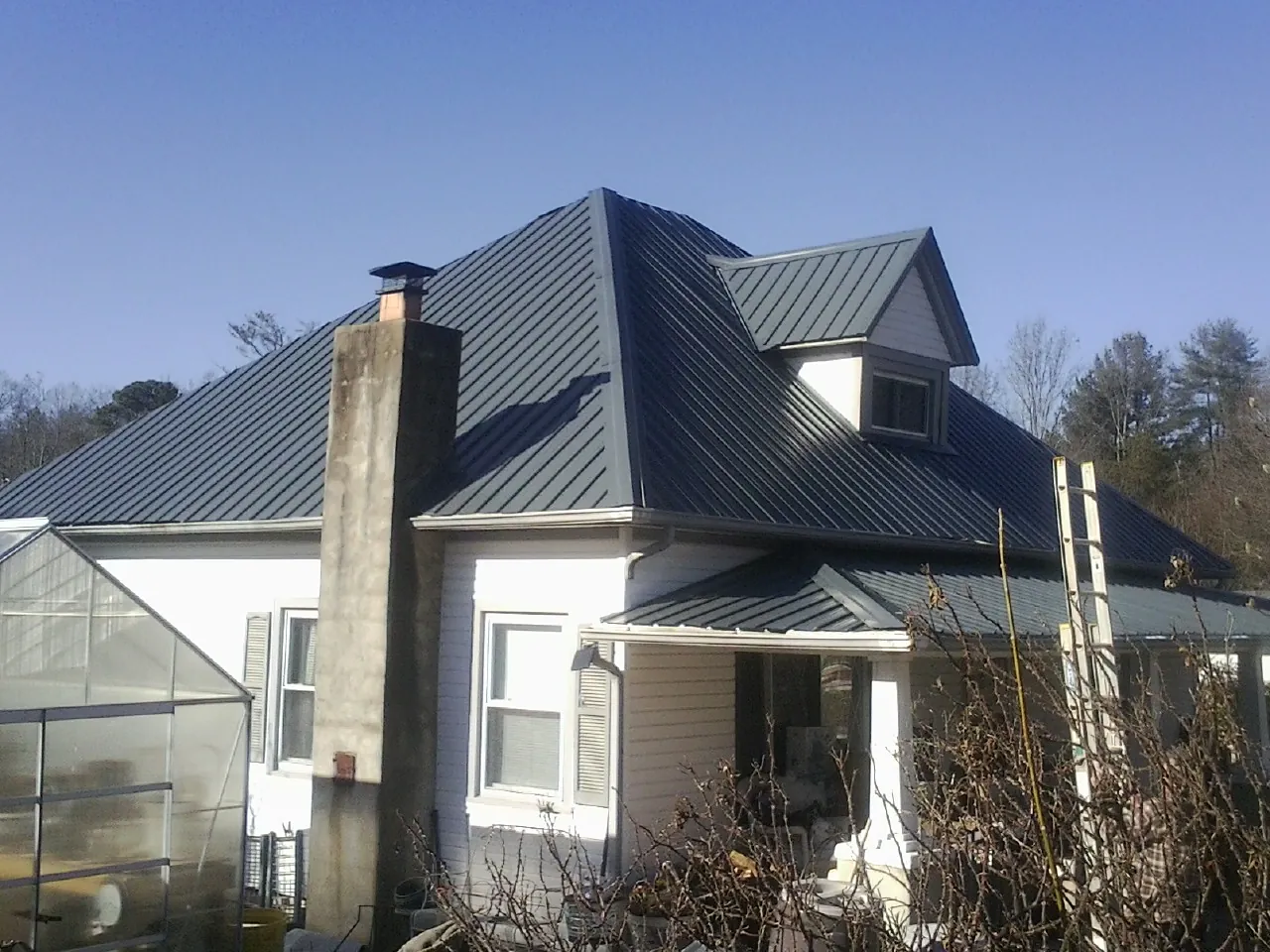 Dark blue standing seam metal roof on a white farmhouse with dormer — Slate & Tile Roof Repair by Roofing Brothers in Kanaranzi