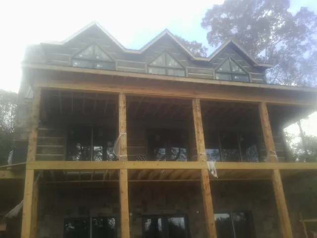 Dormers and porch framing on a large log home under construction — Roof Coating work by our crew in Kanaranzi